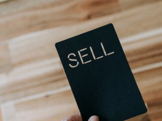 une personne tenant un livre noir sur lequel est écrit le mot « vendre »