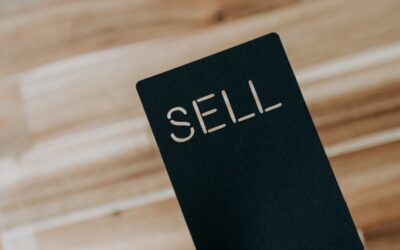 une personne tenant un livre noir sur lequel est écrit le mot « vendre »