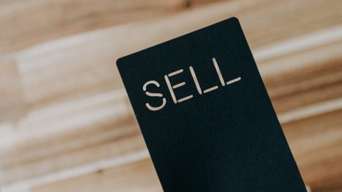 Support client une personne tenant un livre noir sur lequel est écrit le mot « vendre »